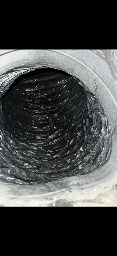 View looking into a clean black flexible air duct with a galvanized metal collar